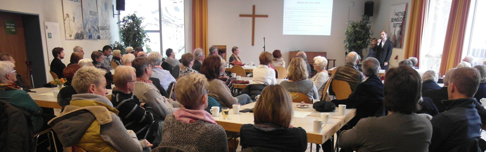 Mitarbeiter sitzen im Saal des Gemeindehauses